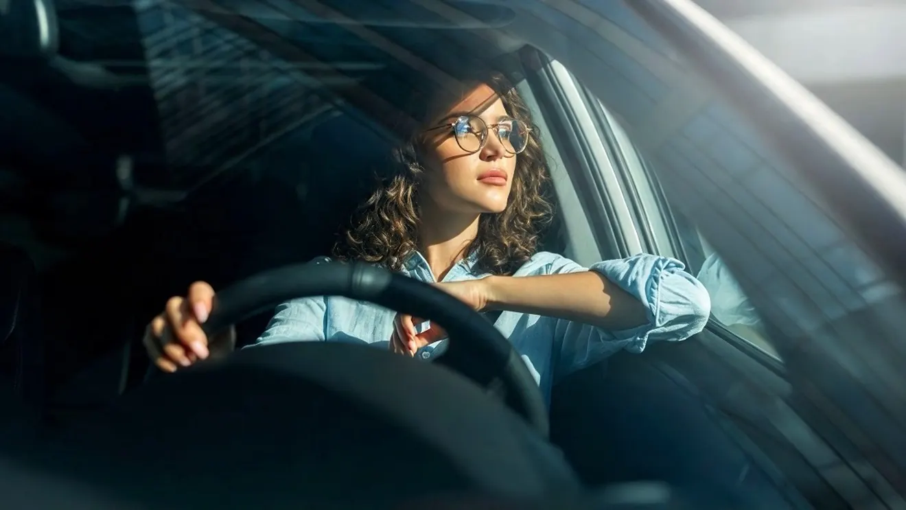 Mujer manejando su carro con la luz de la tarde